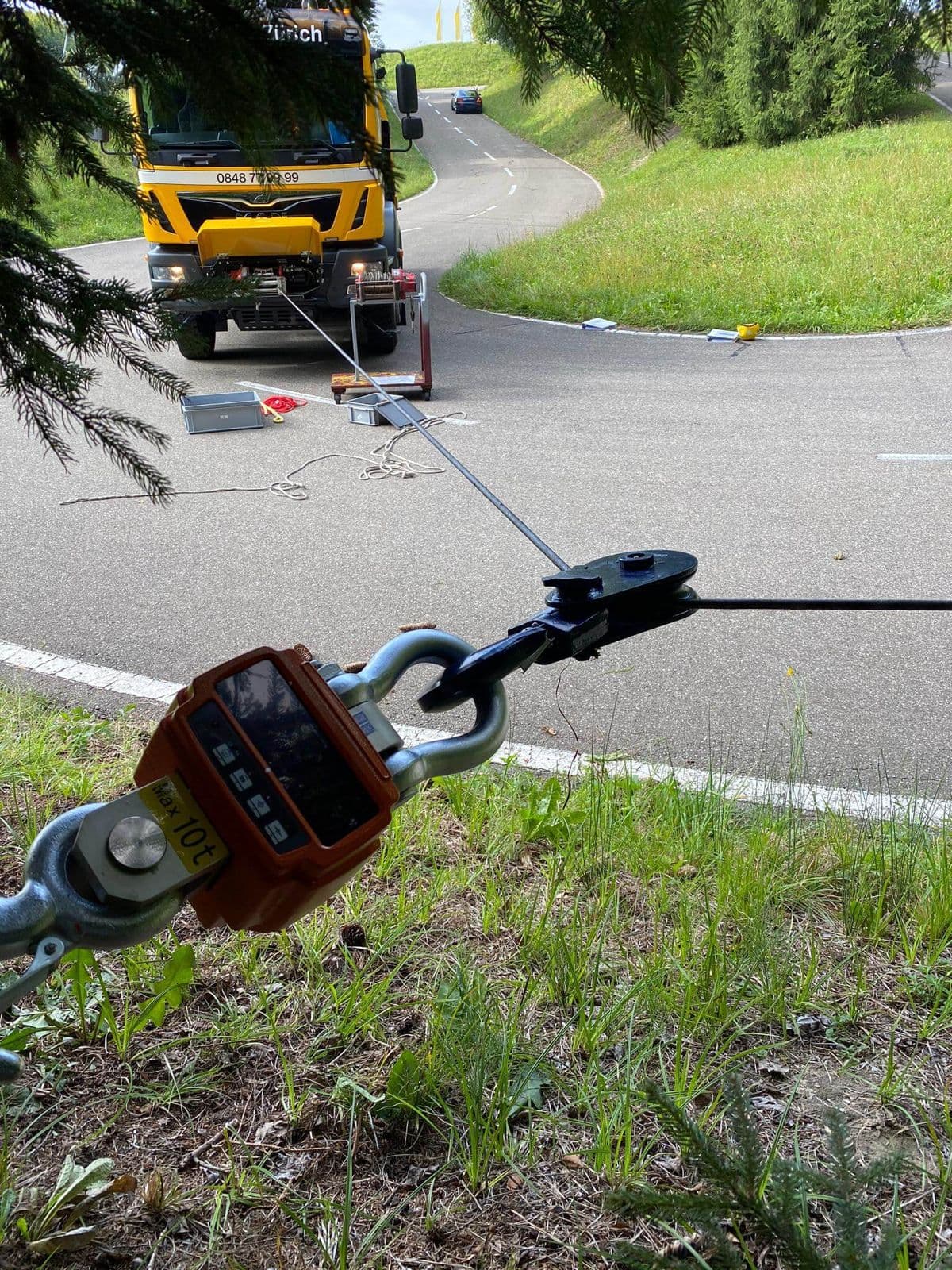 Kranwaage am Seil, dahinter ein Bergungsfahrzeug auf der Strasse